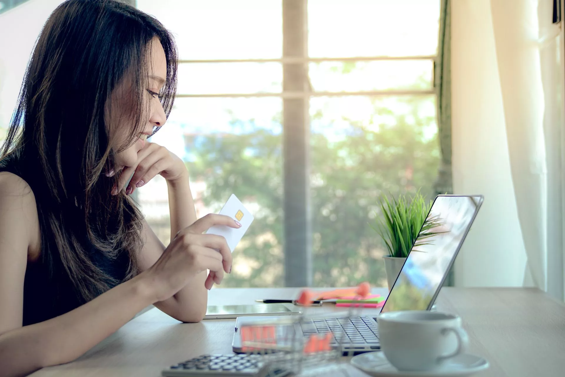 202602131860.webp 年輕女性手持信用卡在筆電前進行線上交易與費用試算,示意「線上刷卡換現金」流程、利率換算與安全申請評估情境