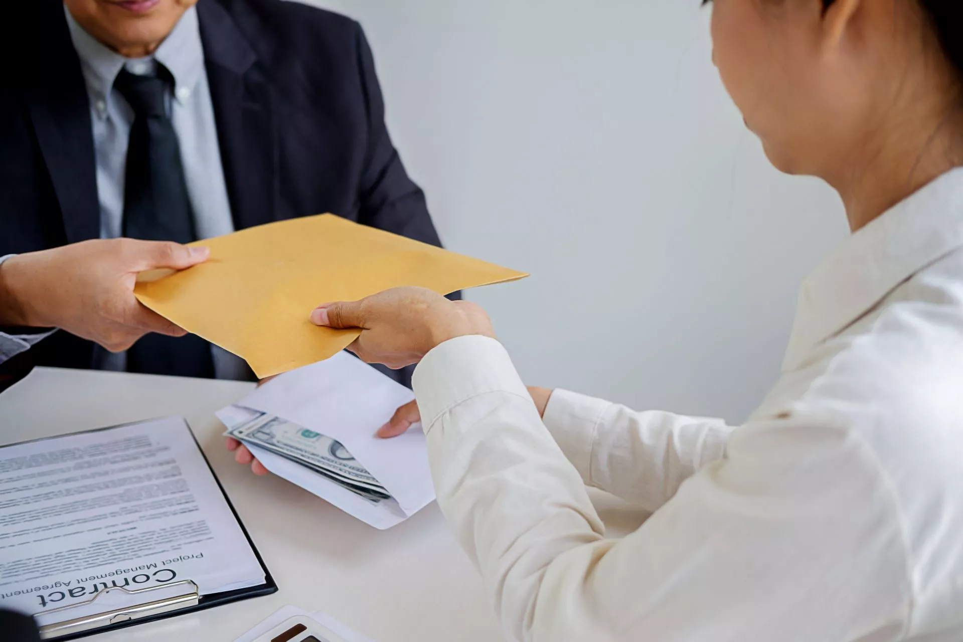 1771985873360159.webp 台中當鋪借款示意圖:客戶與當鋪人員辦理典當流程,遞交信封與現金,桌上擺放合約文件,呈現台中當鋪借款流程、利息計算與合法典當交易情境。