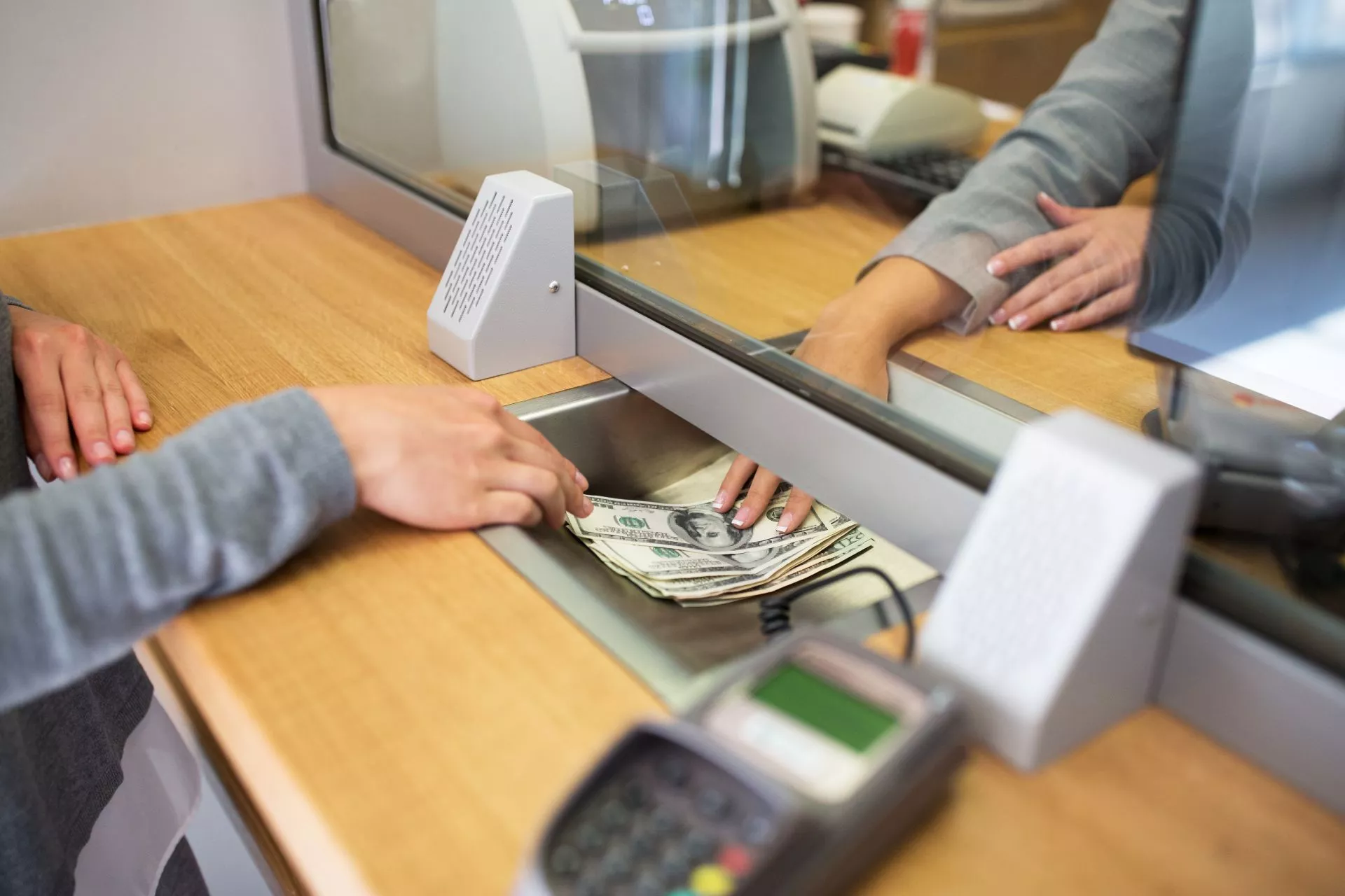 銀行櫃檯人員遞出現金給客戶，呈現現金提領、資金週轉與信用卡預借現金相關情境